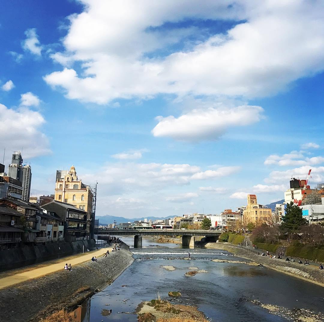 The Kamo River and riverside buildings in Kyoto beneath a blue sky